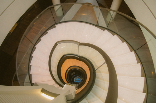 Free Elegant spiral staircase with glass railing in modern building interior. Stock Photo
