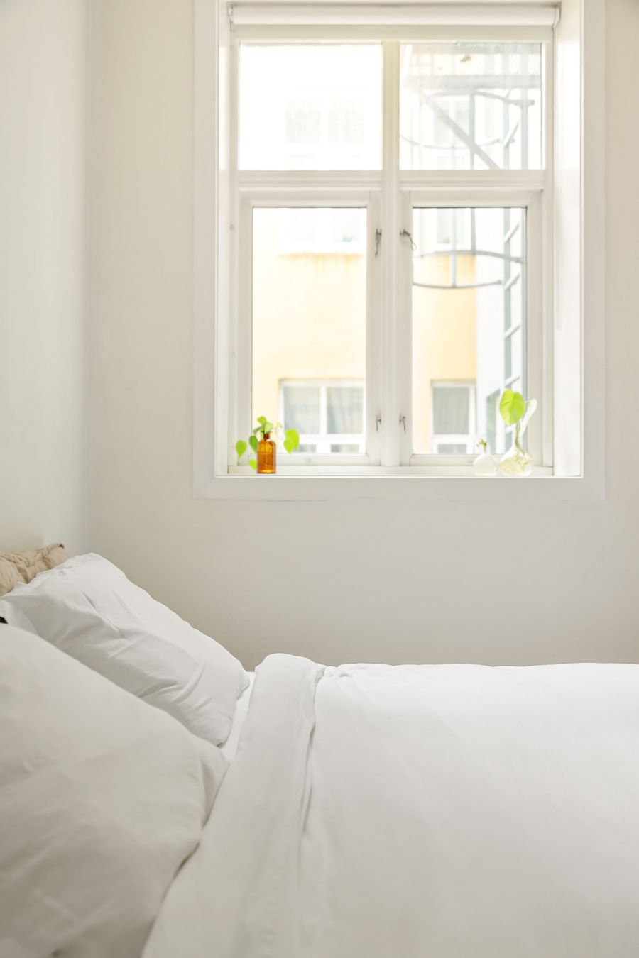 A bright, airy bedroom with crisp white bedding and an open window letting in fresh air.