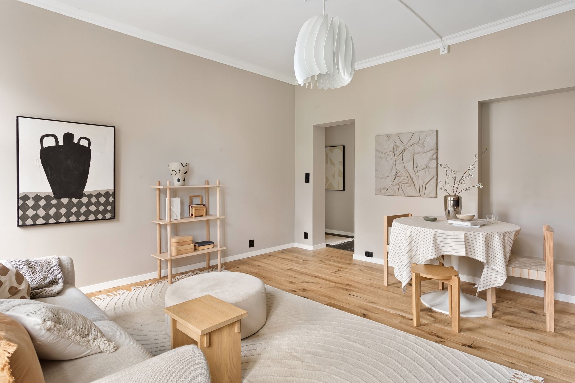 Sunlit Scandinavian living and dining space in warm beige tones with light wood floors