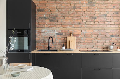 Free Interior of a Modern Kitchen with Black Cabinets and a Brick Wall  Stock Photo