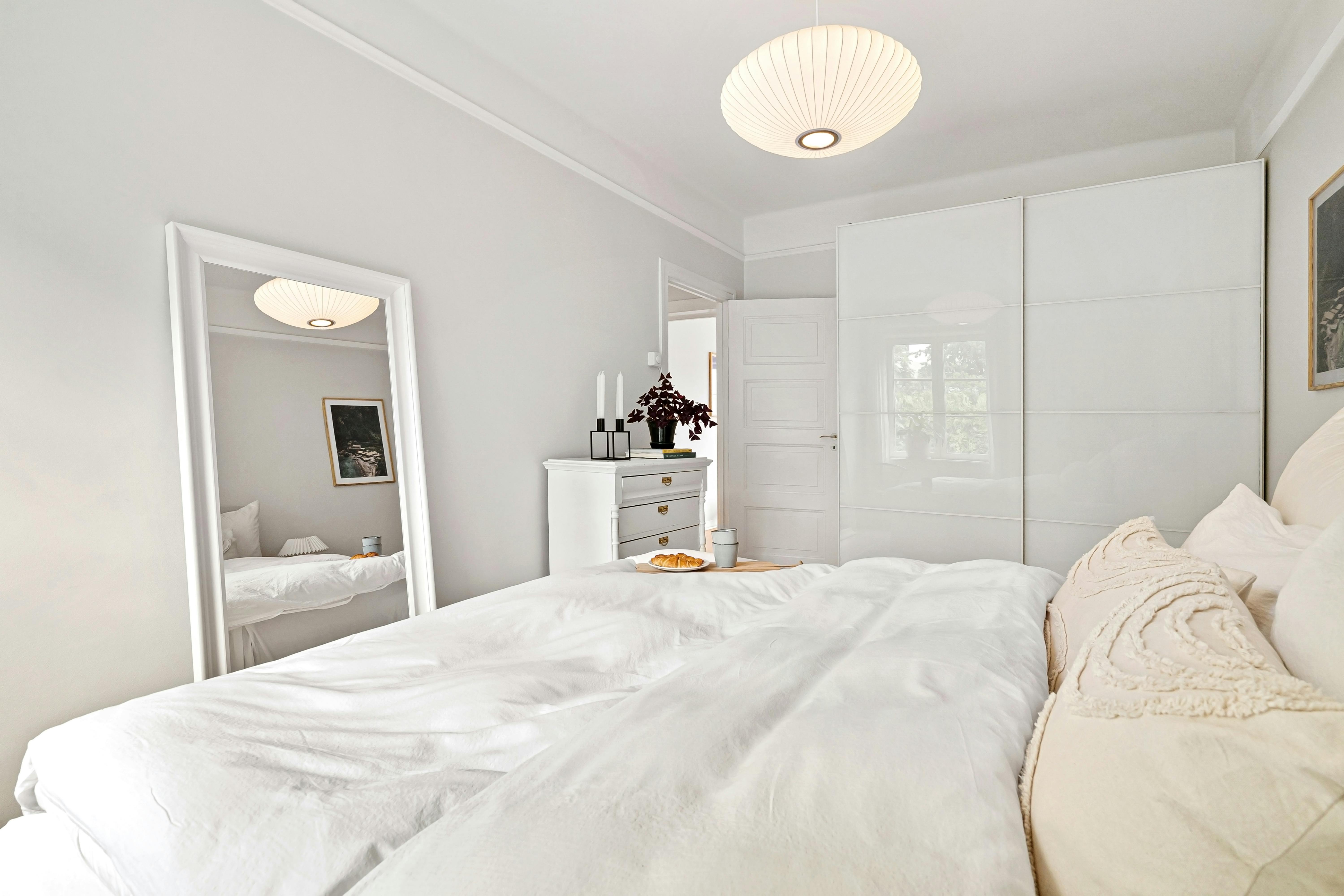 Altbau-Schlafzimmer mit weißem Kleiderschrank und sauber ausgerichteten Türen an ungerader Wand