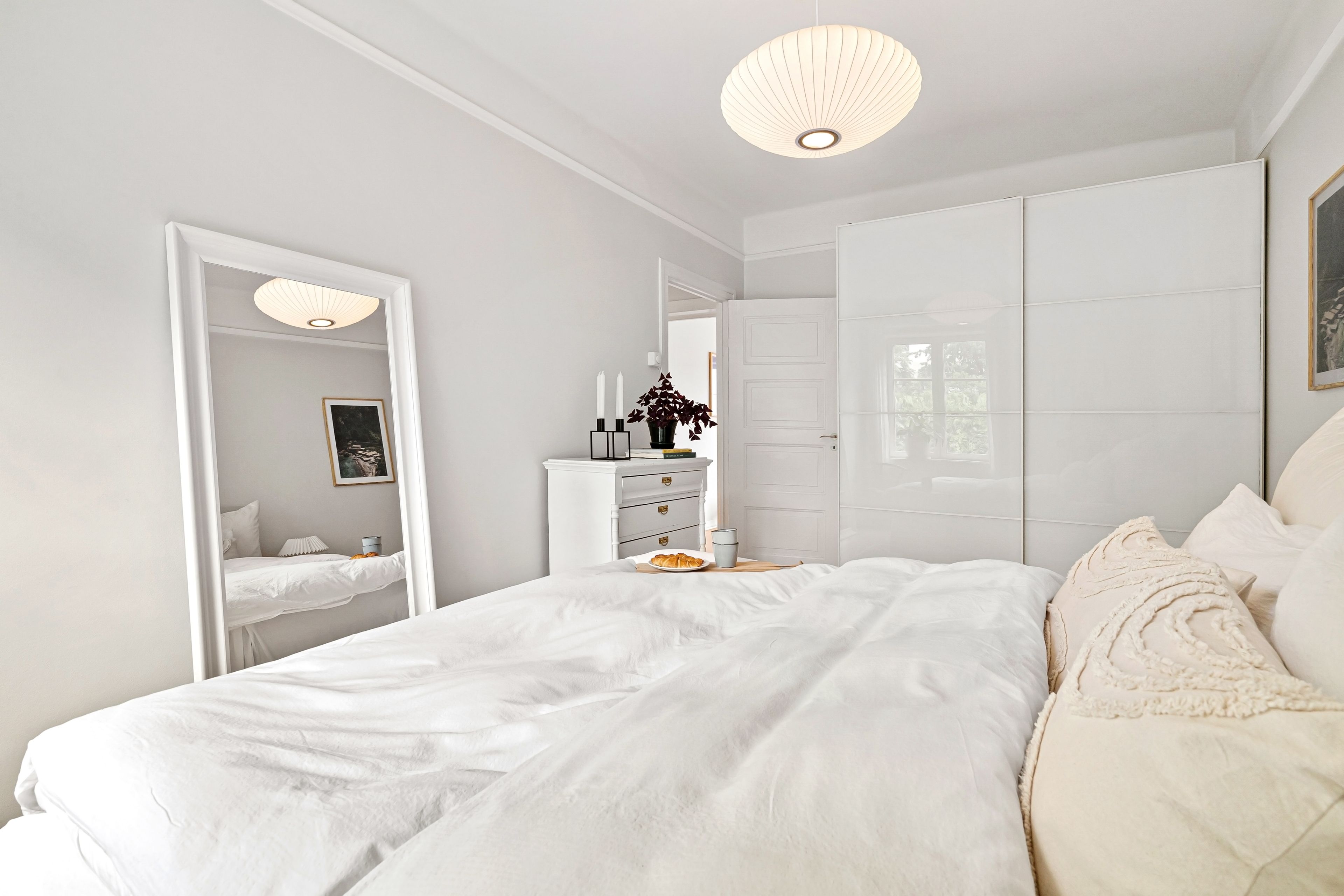 Bright bedroom with a tall mirror and drawer storage furniture