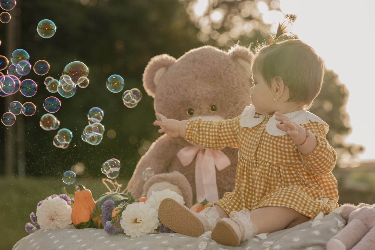charming outdoor scene with a baby interacting with bubbles and a tedd