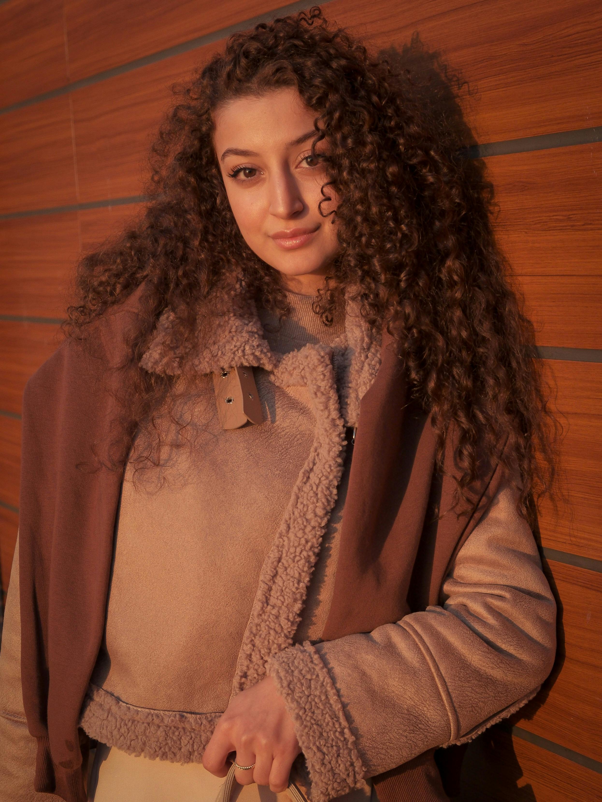 Stylish portrait of a woman in fur-lined coat against wooden wall in Istanbul.
