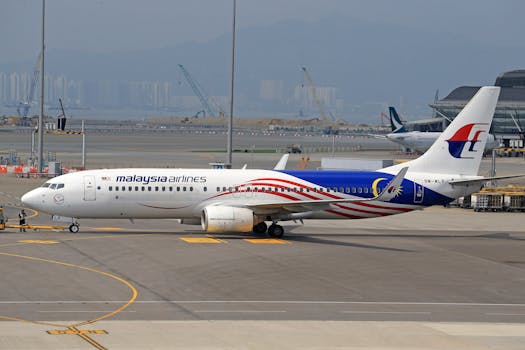 A Malaysia Airlines aircraft positioned at an airport gate, ready for departure on a clear day.