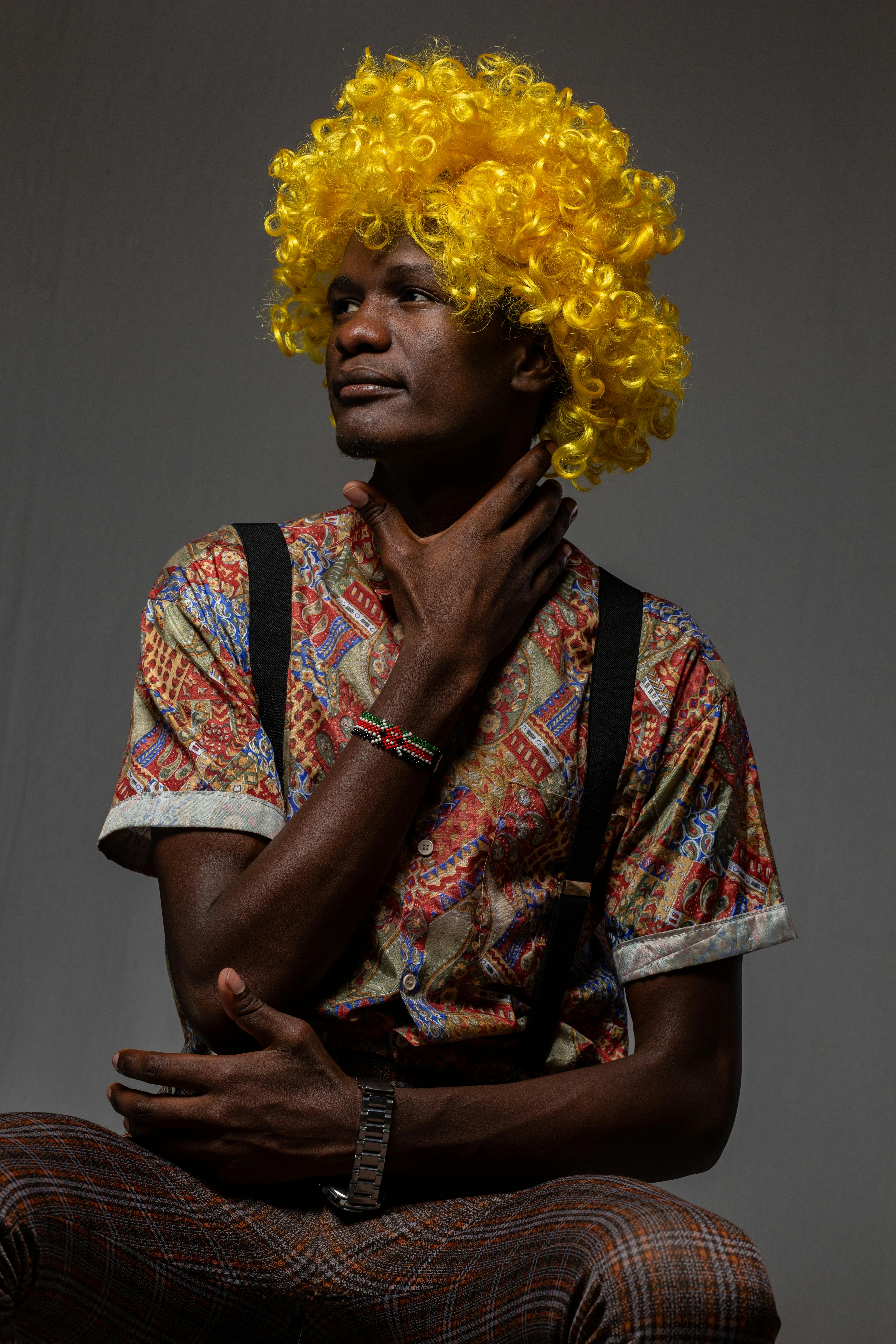 Portrait of a person with an afro wig, vibrant shirt, and suspenders.