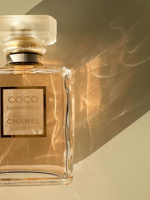 Free Chanel perfume bottle casting a shadow on a white surface, evoking luxury and elegance. Stock Photo