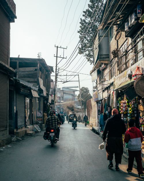 Free A bustling urban street scene with people, scooters, and shops, conveying daily city life. Stock Photo