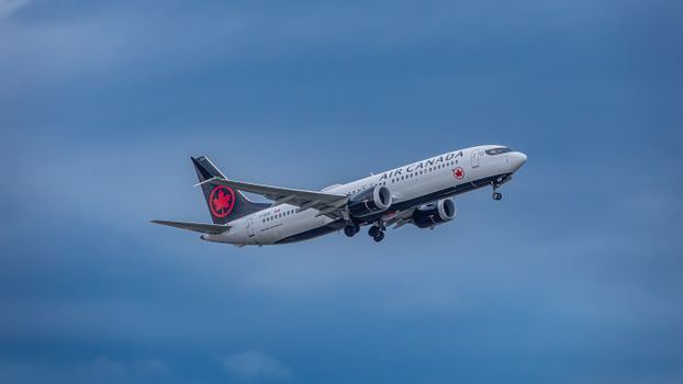 Air Canada aircraft captured mid-flight against a vibrant blue sky.