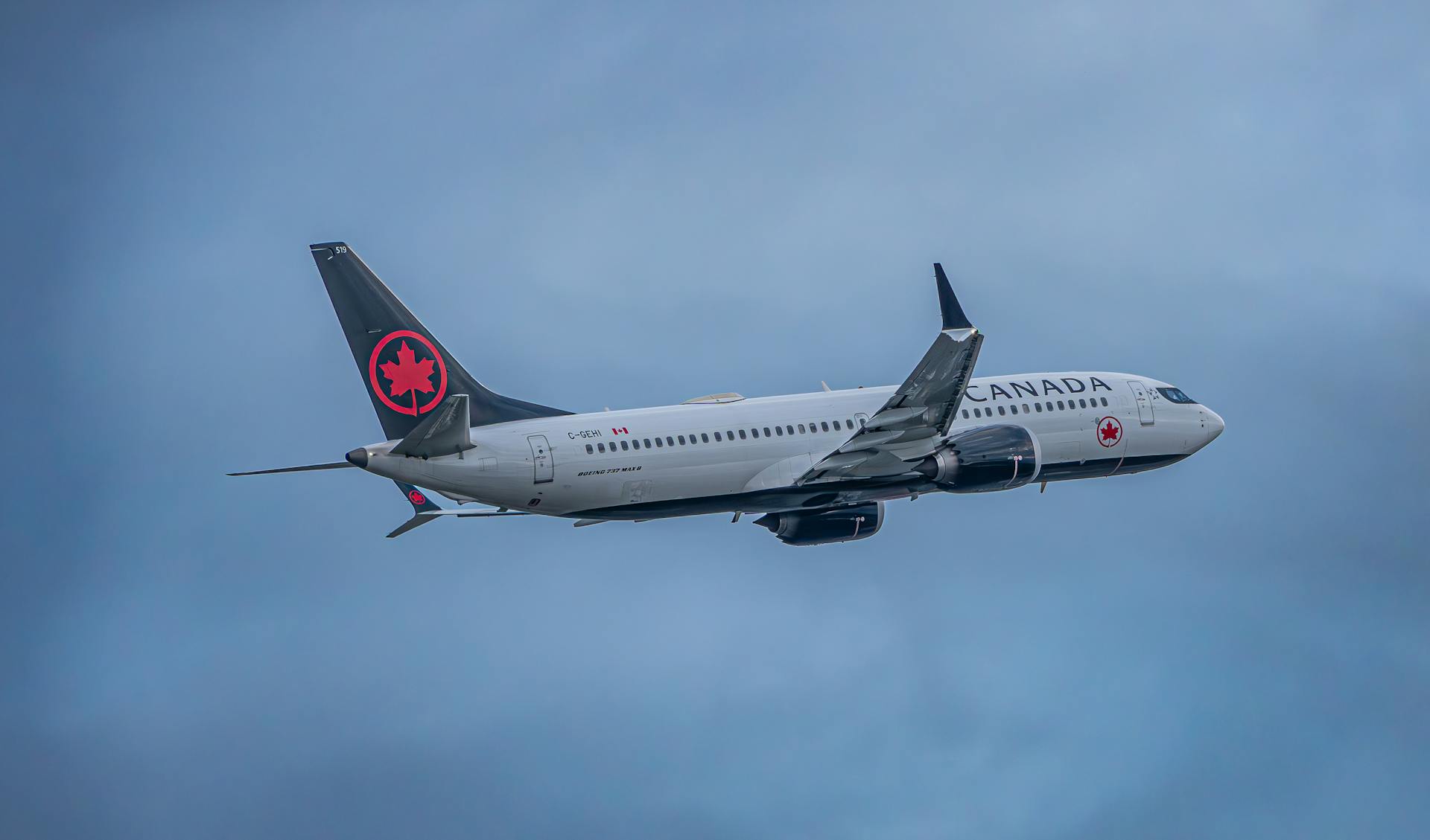 Air Canada airplane soaring through a cloudy sky, showcasing aviation travel.