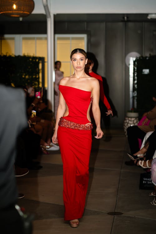 Free Model wearing a striking red dress on the runway at a fashion event, showcasing elegance and style. Stock Photo