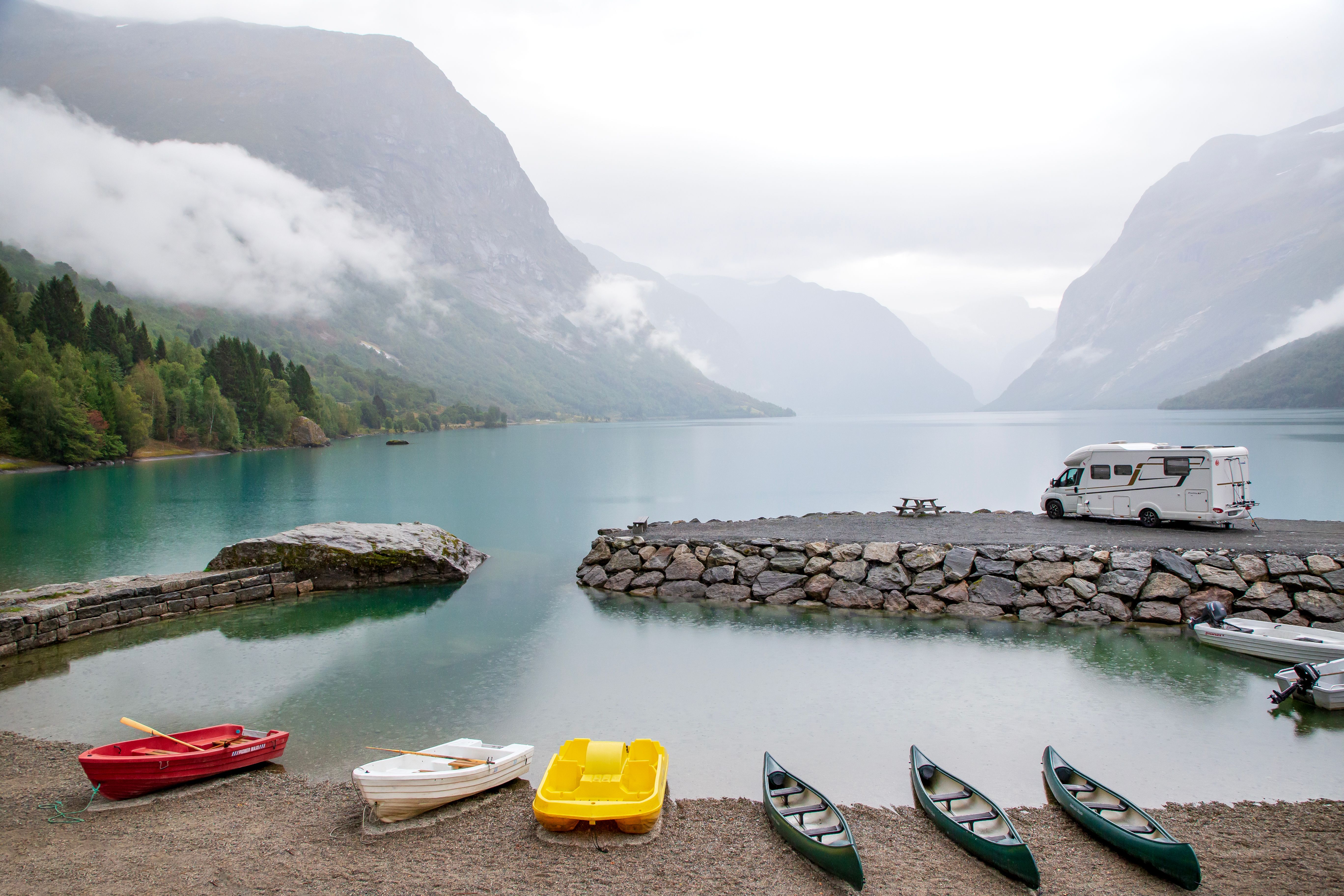 Stunning vista of canoes and mountains by Loen Lake in Norway, capturing serene natural beauty.