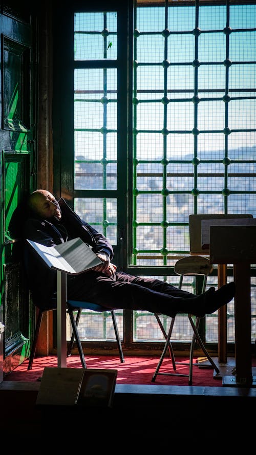 Man Lying Down on Chairs near Windows