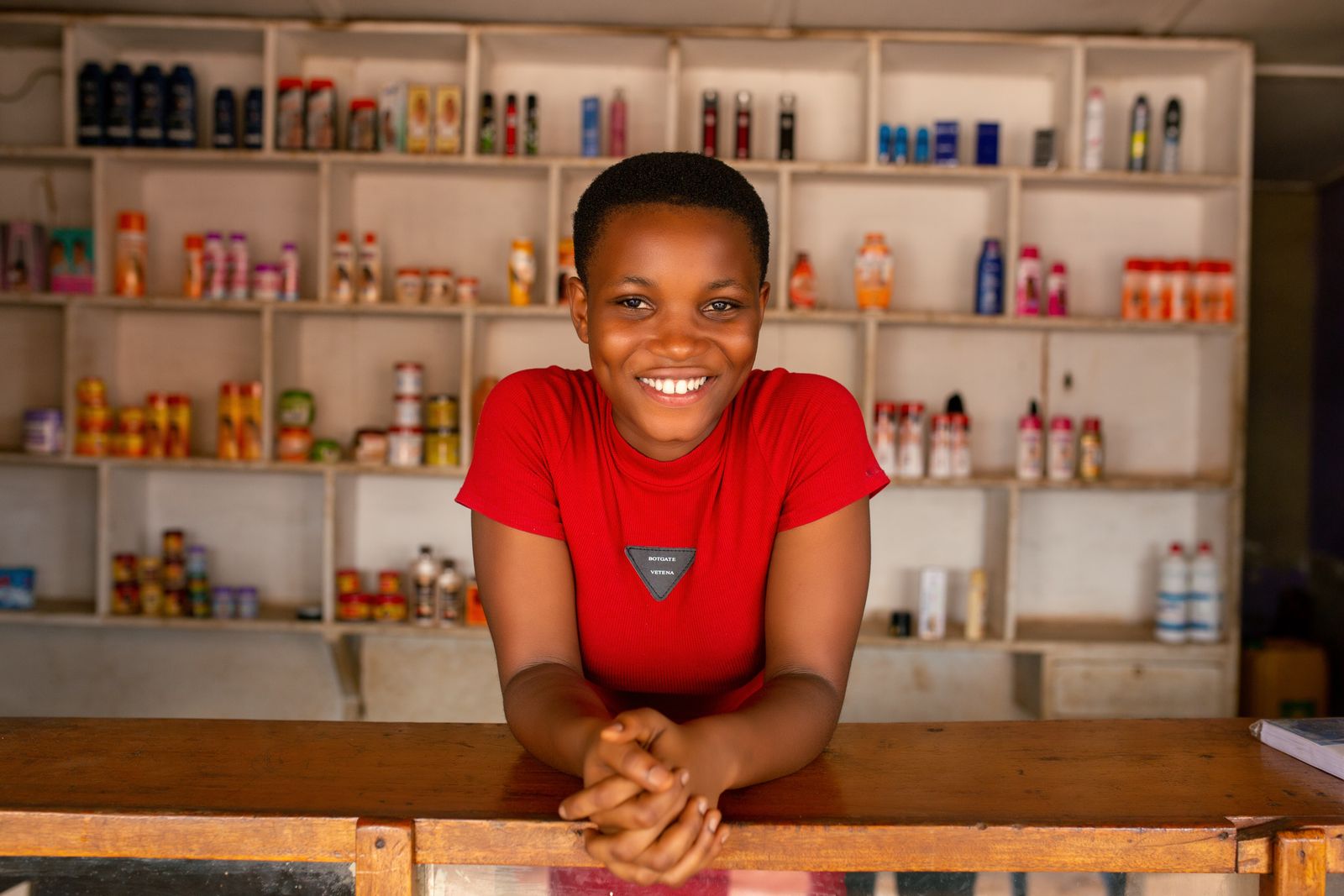 Shopkeeper standing behind a counter inside a stocked store