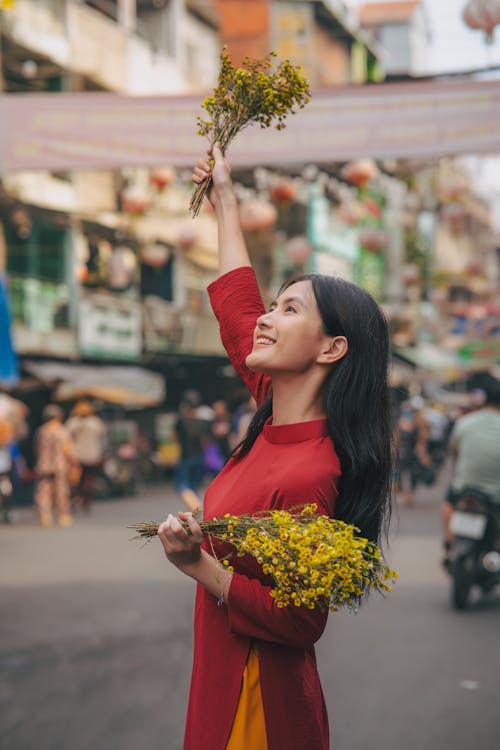 Smiling Woman Standing with Flowers in Raised Arm