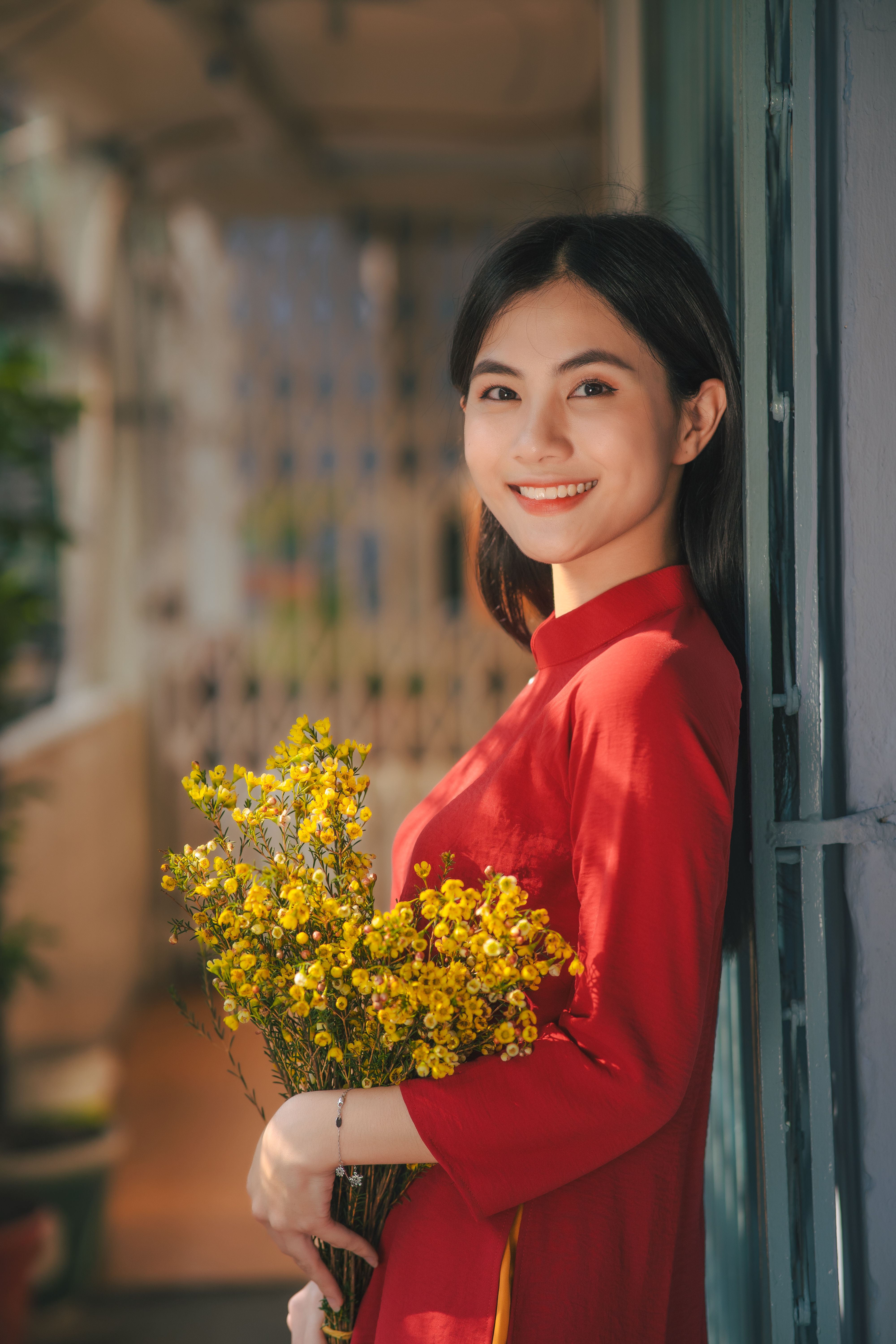 A woman in red holding a bunch of yellow flowers · Free Stock Photo