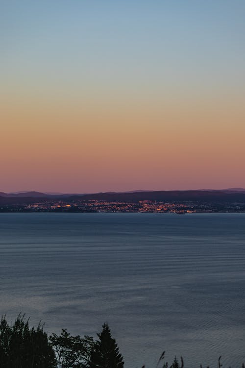 View of a Body of Water and Town in the Horizon at Sunset