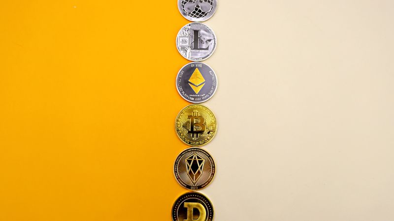 A row of cryptocurrency coins including Bitcoin, Ethereum, and Dogecoin on a vibrant yellow surface.