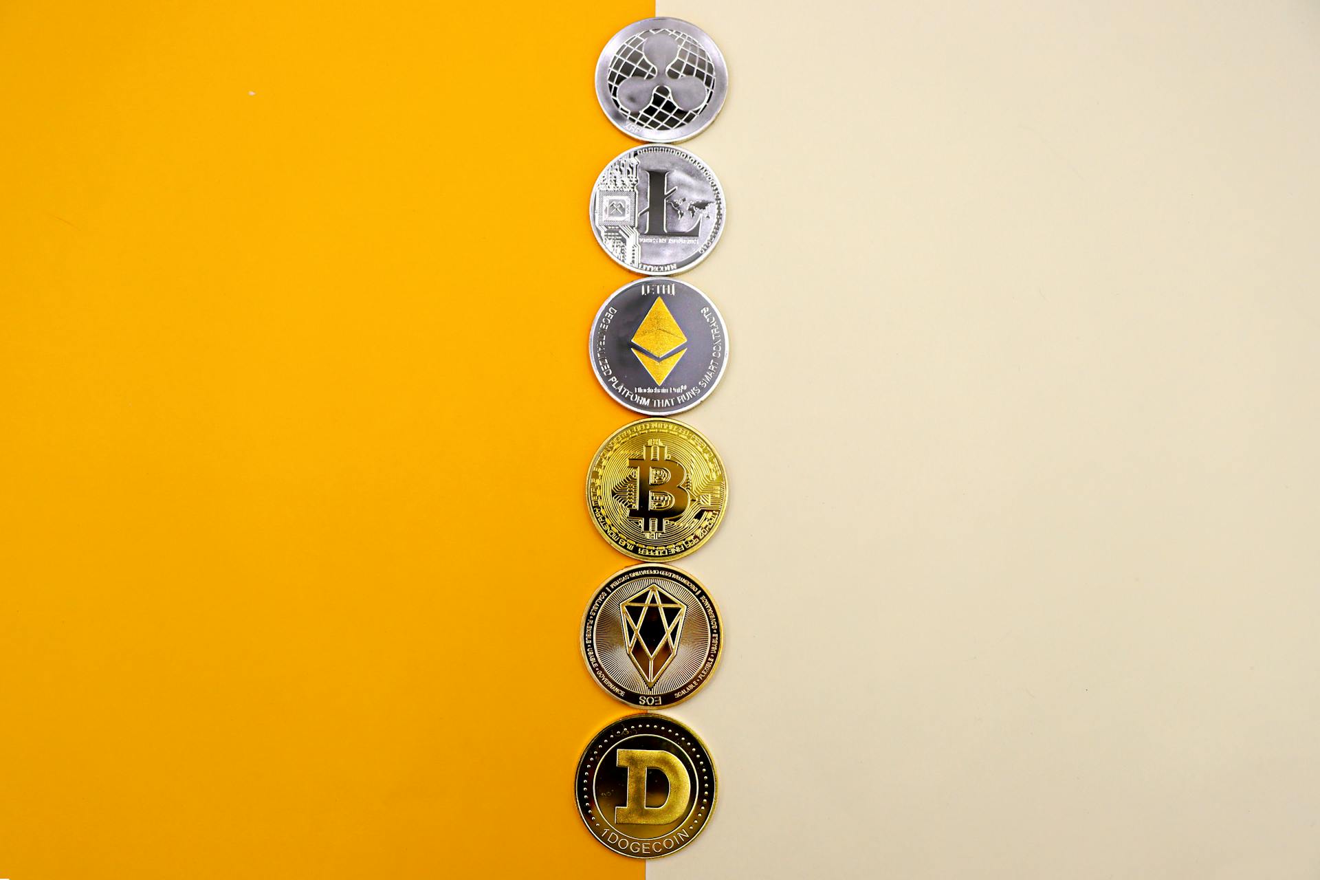 A Line of Cryptocurrency Coins Lying on Yellow and White Background