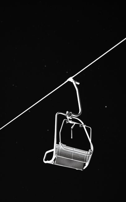 Minimalist photo of a lonely ski lift silhouetted against a dark, starry sky, conveying isolation.