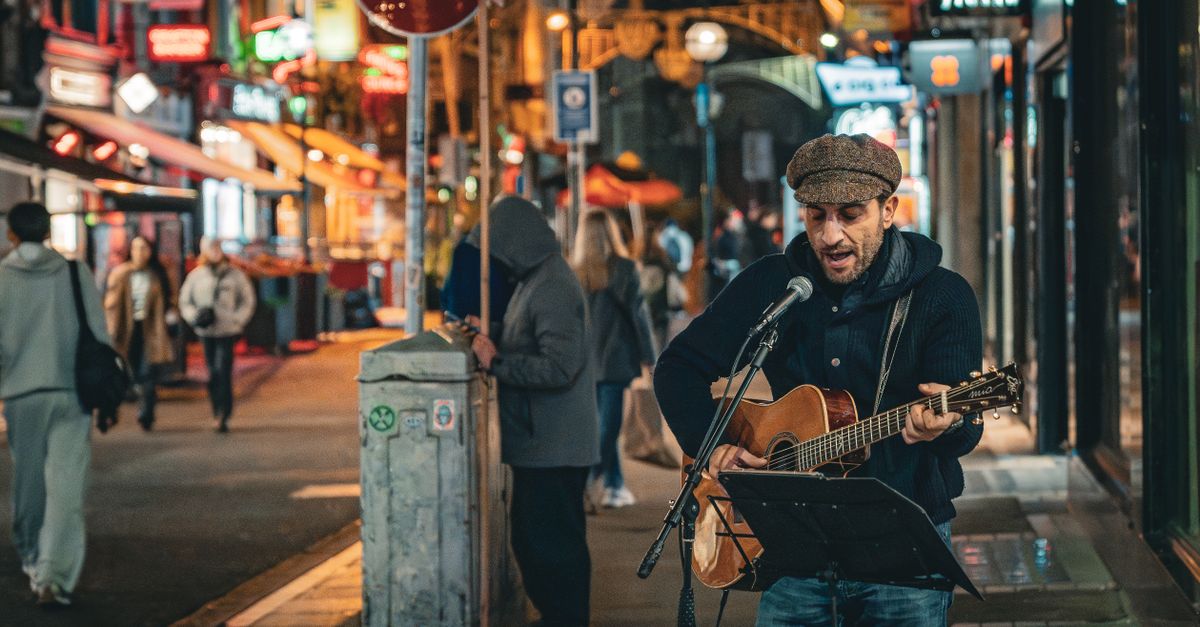A street musician plays guitar and sings on a vibrant Dublin street at night.