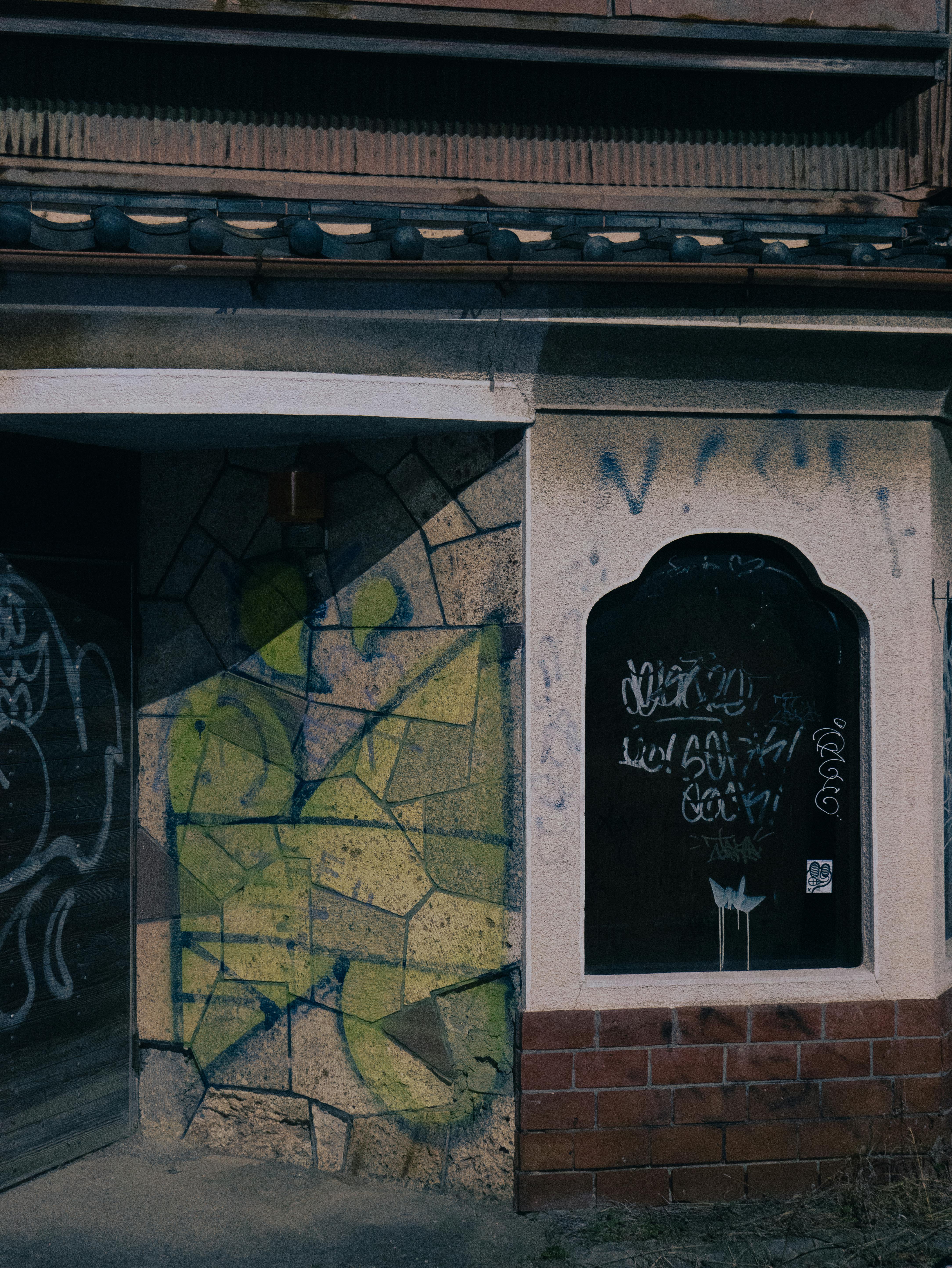 Photograph of an urban building facade with colorful graffiti and street art decor.