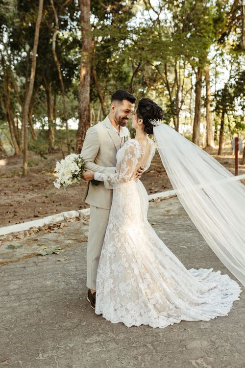 Free Bride and groom embracing outdoors in wedding attire, capturing a tender moment. Stock Photo