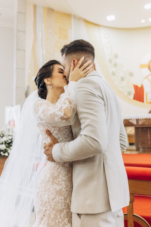 Free Bride and groom share a romantic kiss during their wedding ceremony inside a church. Stock Photo