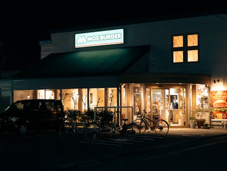 Exterior view of Mos Burger restaurant in Toyohashi illuminated at night, showcasing urban life.
