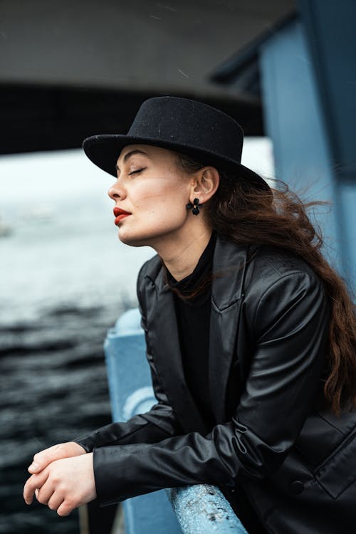 Brunette Woman in Hat and Leather Jacket Posing by Railing