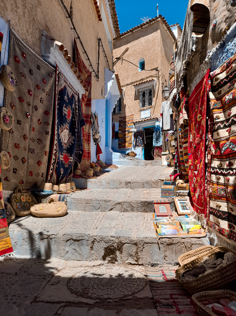 Colorful textiles and crafts on display in Chefchaouen's narrow alleyway market.
