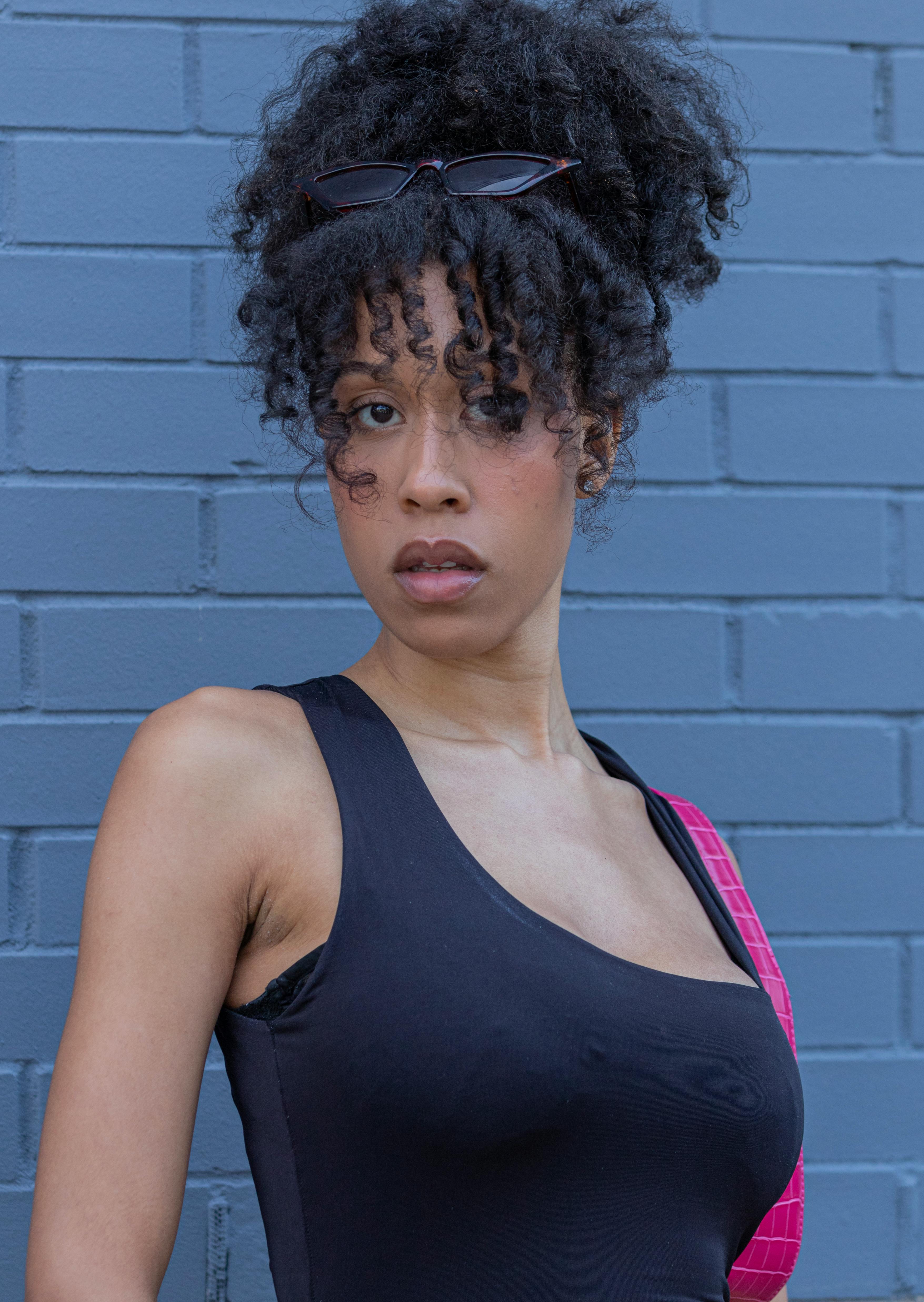 Portrait of a stylish woman against a blue brick wall, exuding confidence and elegance.