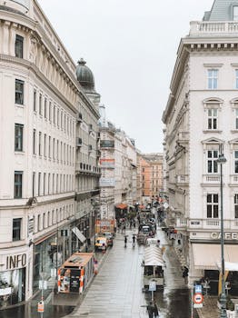 A bustling street in Vienna featuring classic architecture and city life on a rainy day.