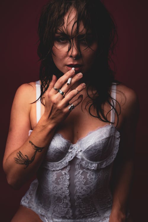 Beautiful Woman in White Corset Posing with Cigarette in Hand