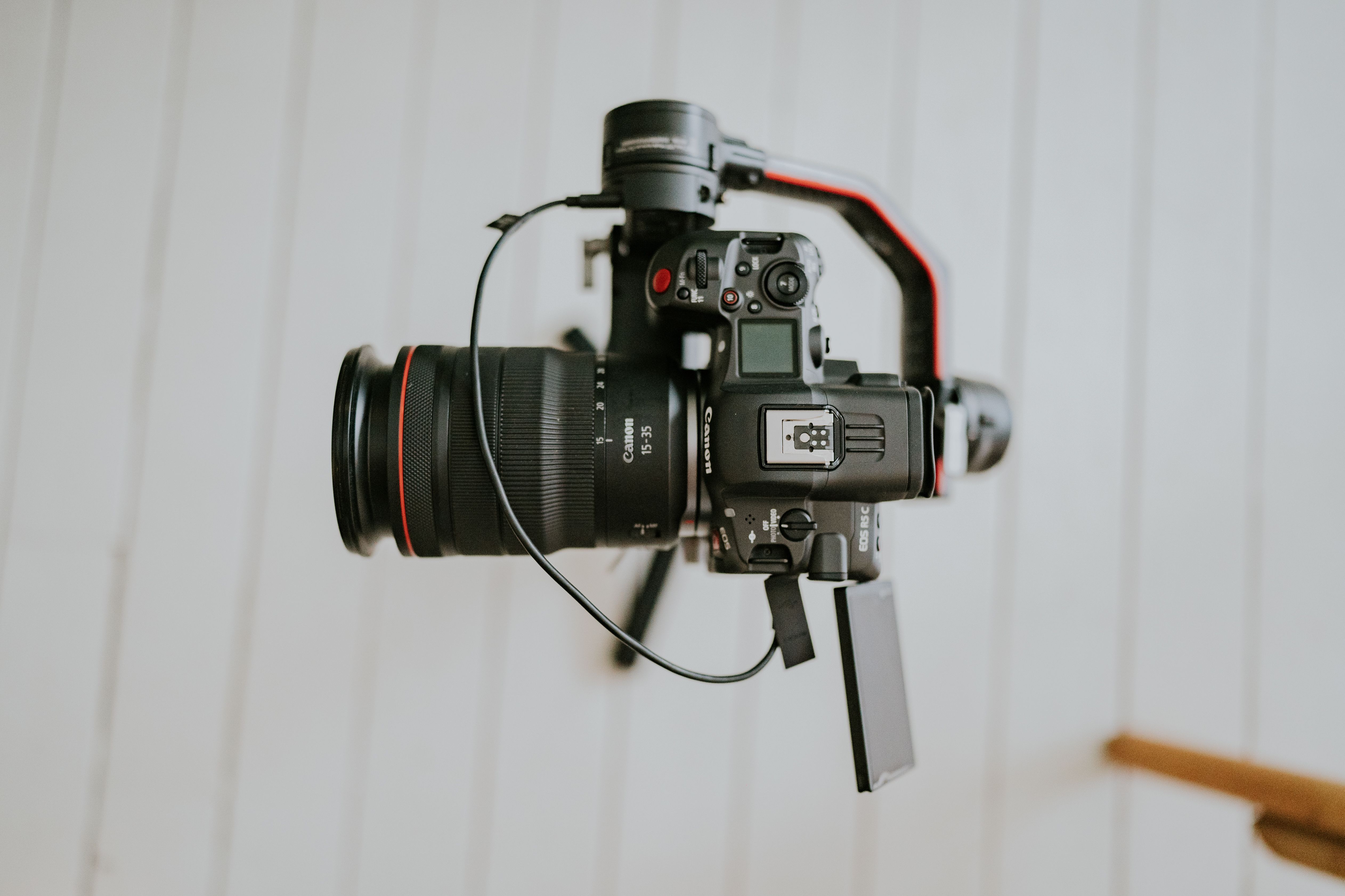 Close-up of a professional DSLR camera mounted on a stabilizing gimbal indoors.