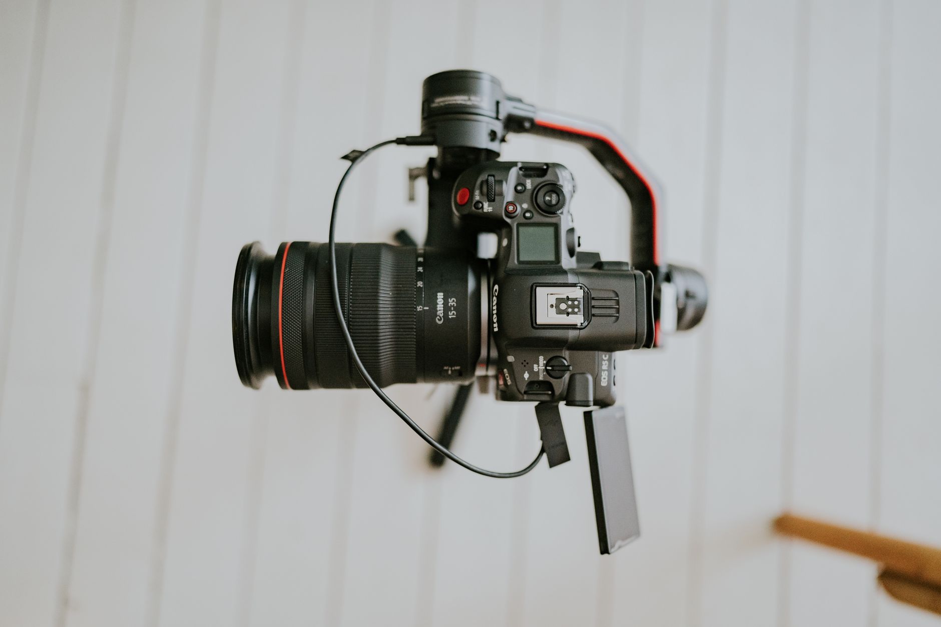 Close-up of a professional DSLR camera mounted on a stabilizing gimbal indoors.