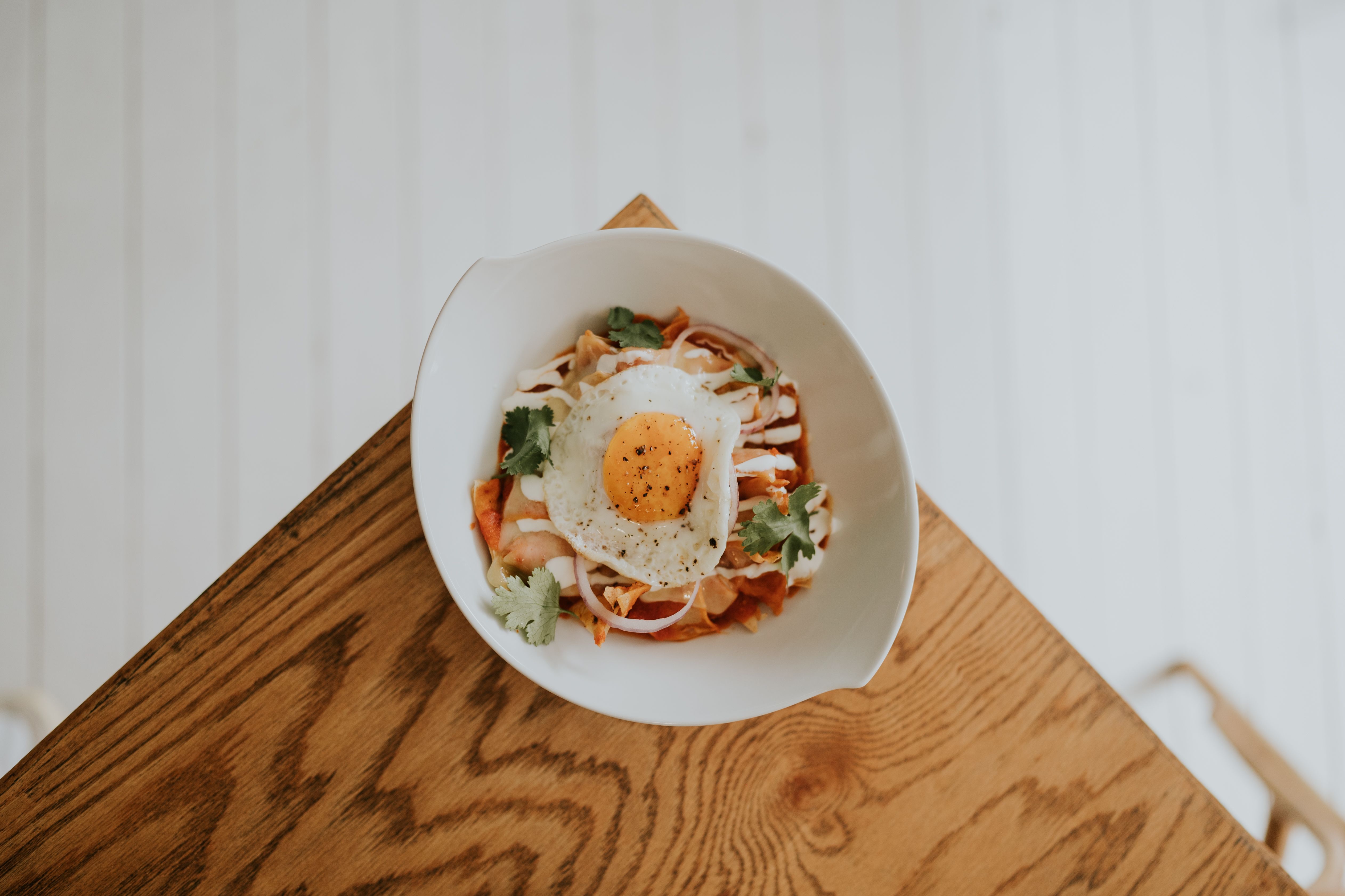 A beautifully plated Korean dish with kimchi and a fried egg on a wooden table, perfect for lunch or dinner.