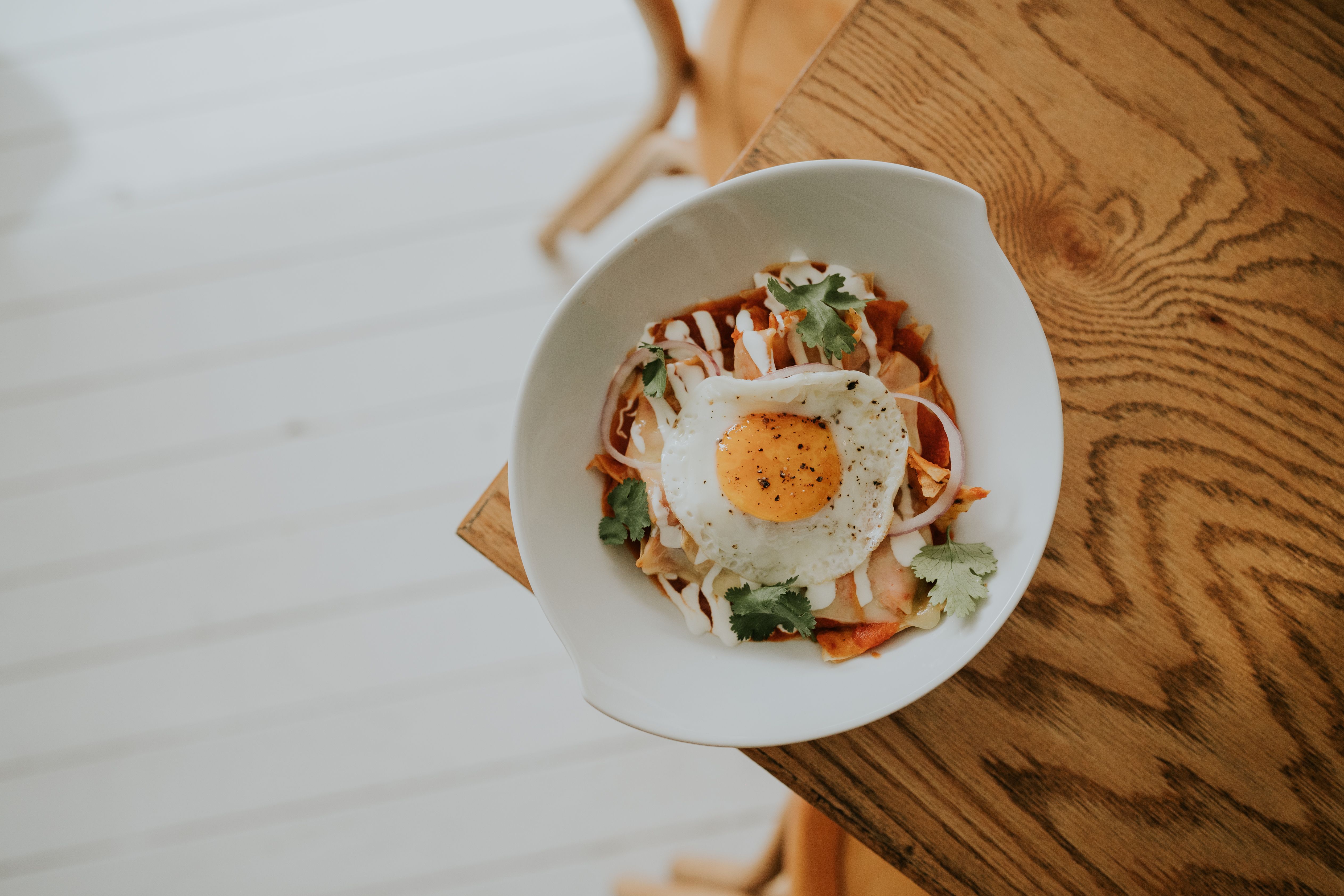 Mouthwatering kimchi dish topped with a fried egg served on a rustic wooden table.