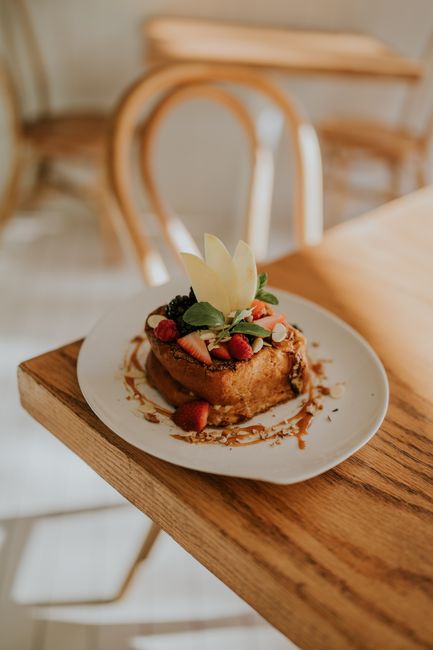 Thick slices of golden-brown sourdough french toast stacked on a plate, dusted with powdered sugar and drizzled with maple syrup.