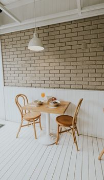 Inviting café interior with brick wall, wooden chairs, and dining table set for two.