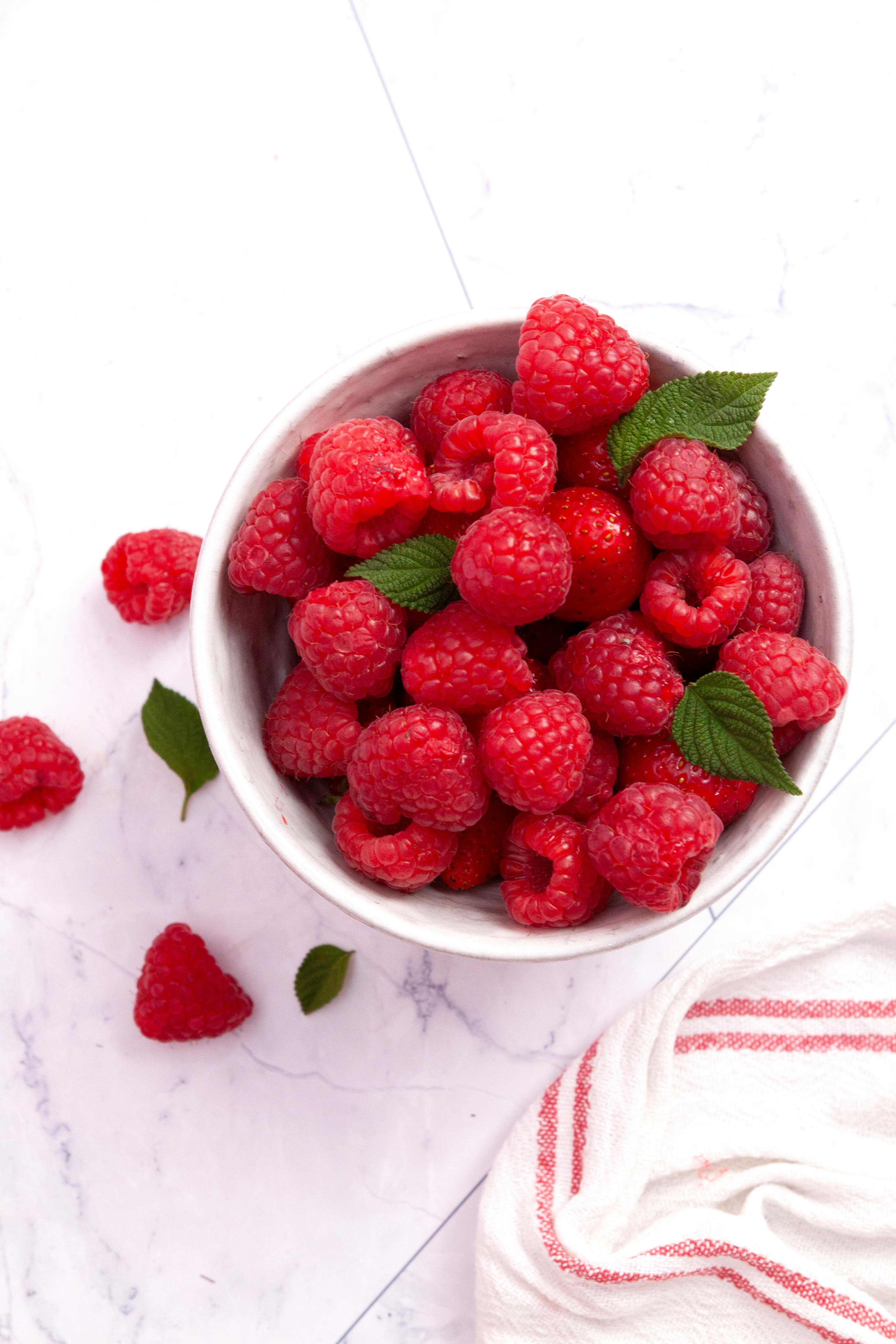 Top view of fresh raspberries in a bowl on a marble surface, perfect for healthy food themes.