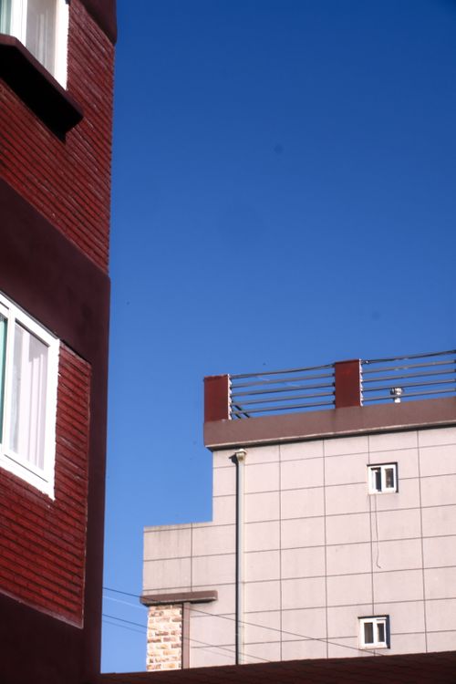 Free Contemporary building rooftops against a vivid blue sky, ideal for real estate imagery. Stock Photo