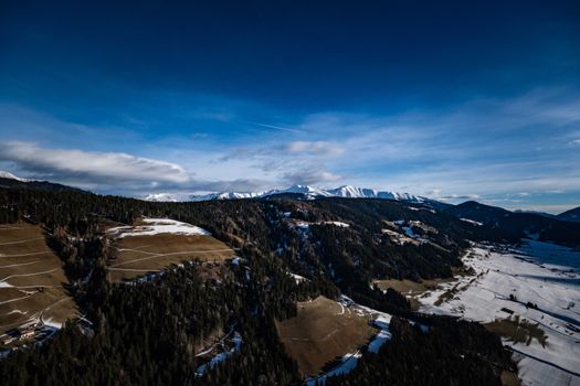 A breathtaking aerial view of snowy mountain ranges and forested hills in winter.