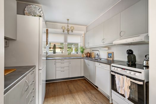 Elegant modern kitchen with minimalist design, featuring cabinets and wooden flooring.