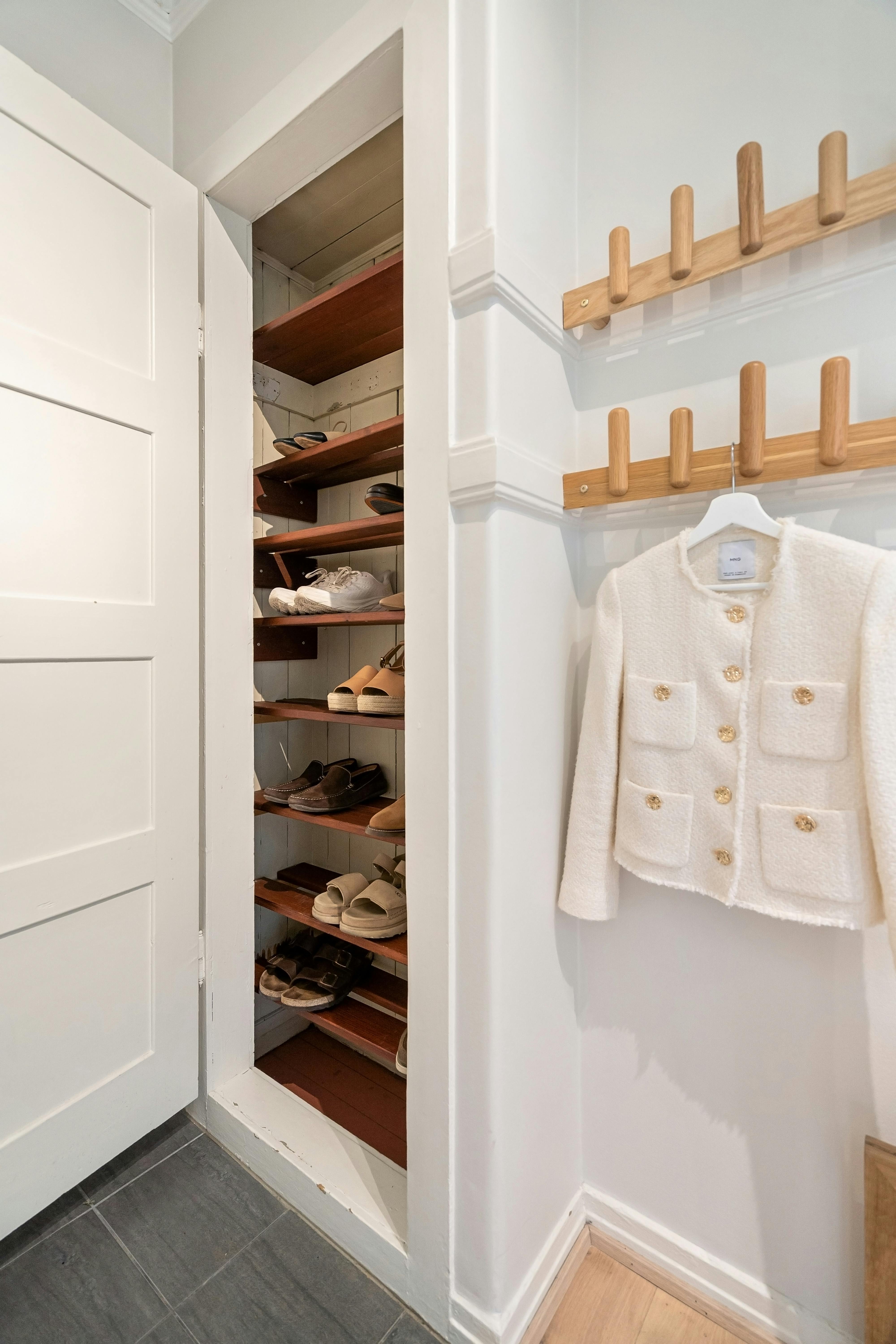Contemporary closet scene with organized shoe storage and elegant coat rack.