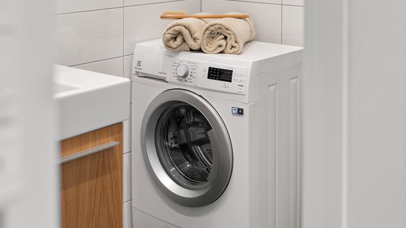 A white washing machine in a home laundry — small white goods and everyday essential lending