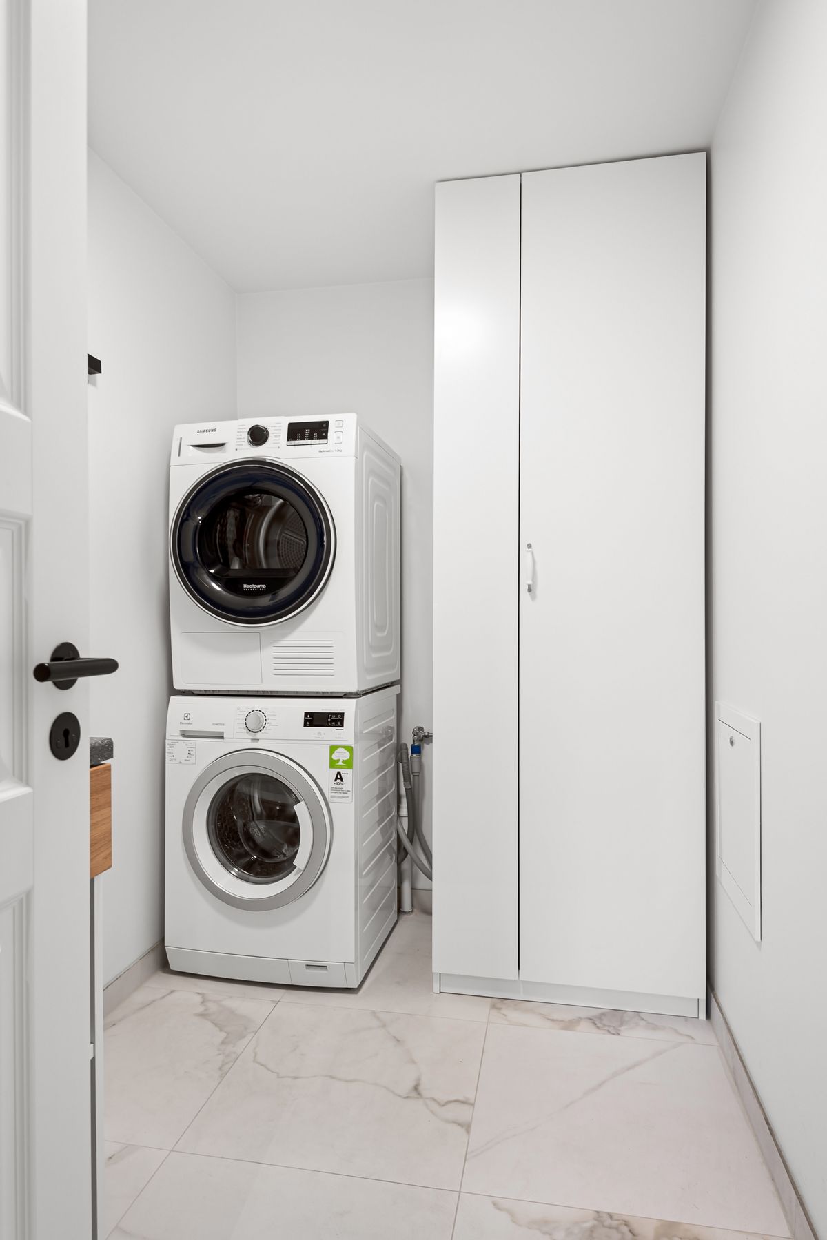 Stacked washer and dryer in a minimalist organized small laundry room with clean lines