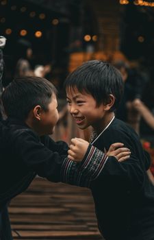 Two smiling boys in traditional attire play together indoors, radiating happiness and fun.