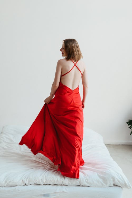 Woman Wearing Elegant Red Dress in Bedroom