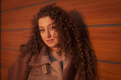 Free A young woman with curly hair posing against a wooden wall in Istanbul, Turkey. Stock Photo